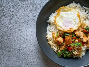 Üstünde kızarmış domuz göbeği, Tayland fesleğeni ve sahanda yumurta var.