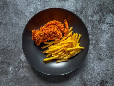 Baharatlı tavuk kanadı ve patates kızartması yemeye hazır.