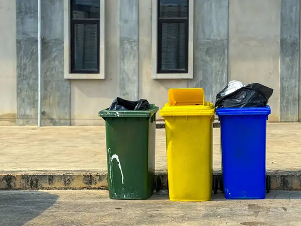 Binanın yanında farklı renkte çöp var.