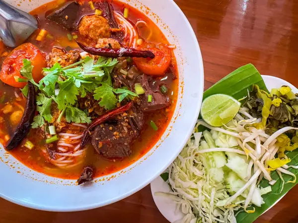 Nam Ngiao adında geleneksel Tayland erişte çorbası yanında taze sebzelerle servis edilir..