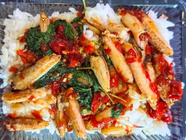 Pirinç üstü kızarmış karides ve kutsal fesleğenle karıştırılmış yiyecek kabı.