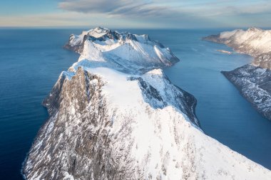 Snow covered mountain range on coastline in winter, Norway. Senja panoramic aerial view landscape nordic snow cold winter norway ocean cloudy sky snowy mountains. Troms county, Fjordgard