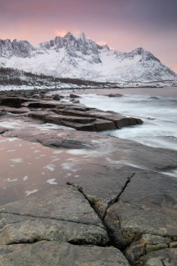 Snow covered mountain range on coastline in winter, Norway. Senja panoramic aerial view landscape nordic snow cold winter norway ocean cloudy sky snowy mountains. Troms county, Fjordgard