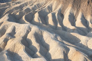 Mesquite Düzlüğü Kum Tepesi 'nde, Kaliforniya' daki Ölüm Vadisi Ulusal Parkı 'nda güneş doğarken oluşan doğal dalgalı kum deseni manzarası. Mojave çölünde sabah yürüyüşü Amargosa sıradağları arkada.