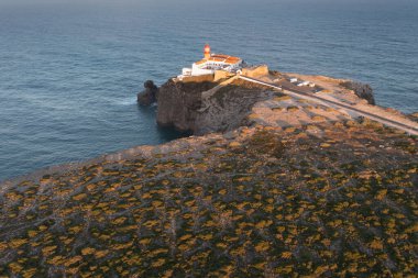 Cabo de So Vicente 'nin engebeli uçurumları üzerinde, Farol do Cabo de So Vicente deniz feneri, Atlantik Okyanusu' nun panoramik manzarası, Algarve bölgesinde bir tatil yeri haline getiriyor. Hava görünümü.