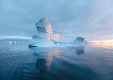 Antarktika 'da buzdağları olan kutup doğası. Ufukta gece yarısı güneş batarken gün batarken. Yaz Gecesi Güneşi ve buzdağları. Buz üzerinde büyük mavi buz. İklim değişikliği küresel ısınma.