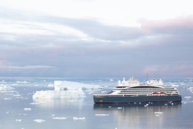 Grönland 'ın güneyindeki Ilulissat limanının yakınındaki demirli yolcu gemisinde. Buzdağları arasında yelken açmak. Küresel Isınma İklimi. Buz erimesini değiştir