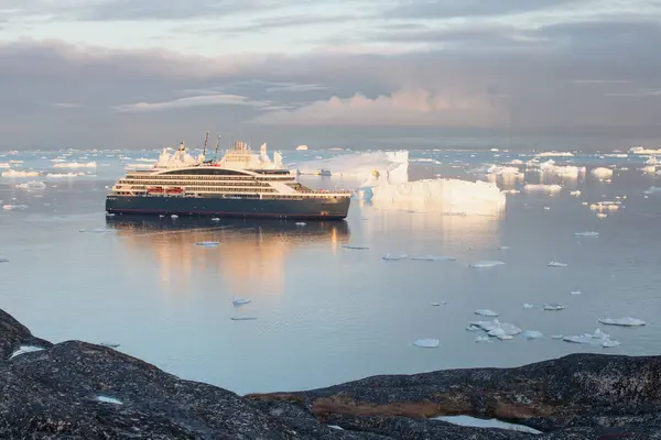The expedition cruise ship at anchor near the port of Ilulissat in southern Greenland. Sailing through the Icebergs. Global Warming Climate. Change Ice melting