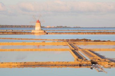 Marsala, Sicilya adası, İtalya 'nın Trapani tuz düzlüklerinde ve Sicilya' nın eski yel değirmeninde tuz buharlaştırma göletinde gün batımı. Güneşli ve güzel bir günde.