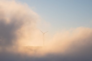 Batan güneşin altında dağlarda rüzgar türbini. Elektrik üretimi için rüzgar enerjisi, sürdürülebilir kaynaklar kavramı. Rüzgardan yenilenebilir enerji.