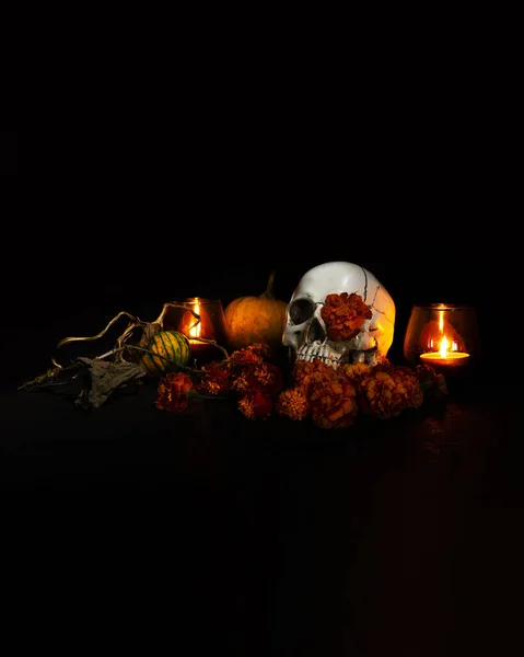 Skull, Burning candles and orange marigold flowers on black background. Concept of Dia de los muertos day or day of the dead. Dark halloween banner.