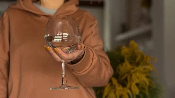 Woman holds a wine glass of clean water. The concept of dry January and sober October. Avoiding alcohol throughout the month. Healthy lifestyle.