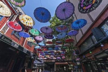 İstanbul, Türkiye - 19 Temmuz 2023: Kadıköy 'ün Şemsiye Caddesi. Birçok renkli şemsiye güneşin ışınlarını engellemek için caddenin ortasında asılı duruyor..