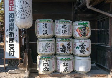 Eski Sake Fıçıları yığıldı. Japon dekorasyonu ve hiyeroglifleri her varilde tasvir edilir..