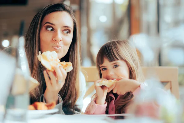 Hungry Mom and Daughter Having Pizza in a Restaurant