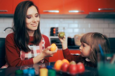 Mother and Daughter Knocking Easter Eggs at Home