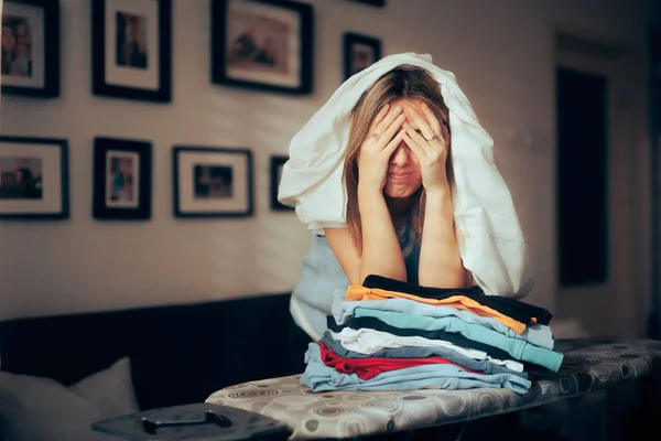 洗濯の山をアイロンをかけなければならないストレスの多い絶望的な女性 — ストック写真