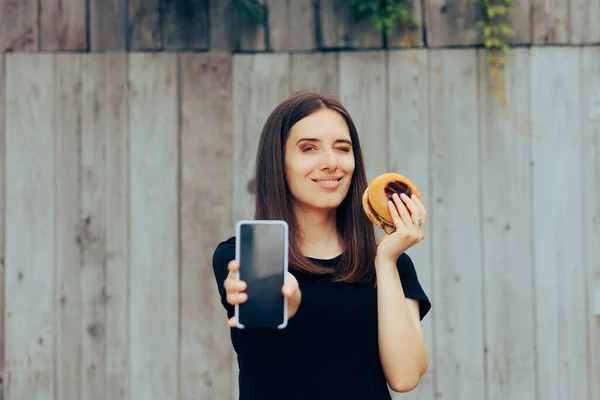 Happy Woman Holding Burger Showing Smartphone Display — Stock Photo, Image