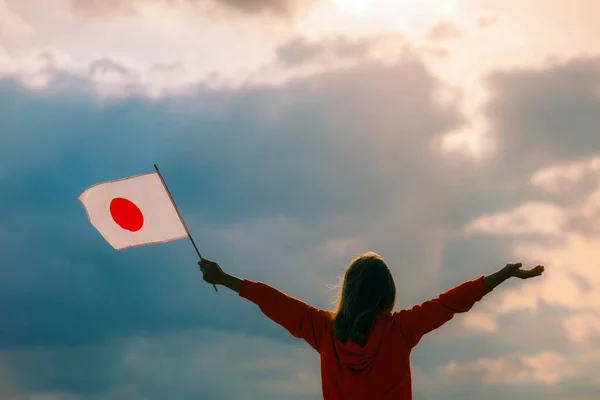 Woman Waving the Flag of Japan on a Beautiful the Sky