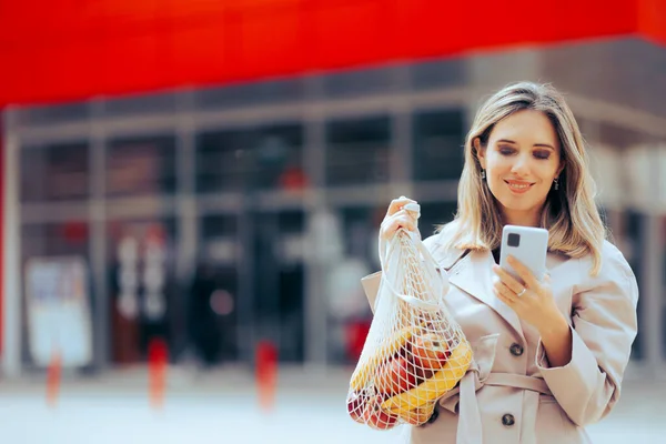 メッシュの食料品袋と携帯電話を保持する幸せな女性 — ストック写真
