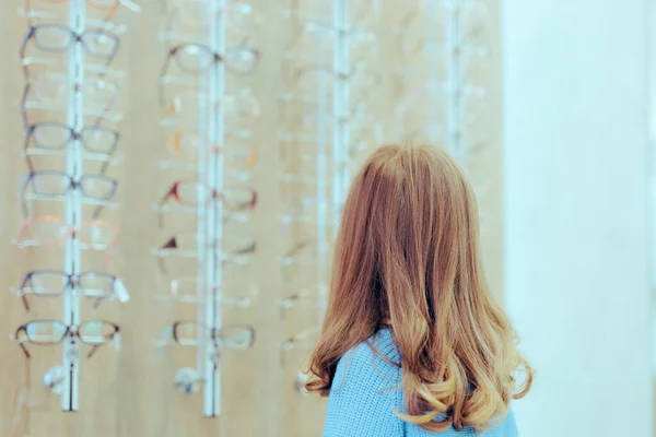 小女孩在一家光学商店里检查眼镜架 — 图库照片