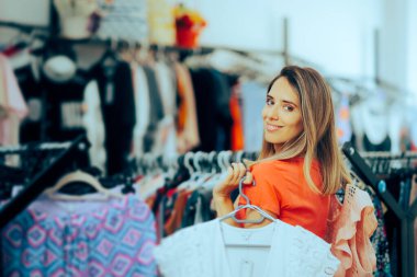 Moda Mağazasında İki Moda Bluzu Tutan Kadın 