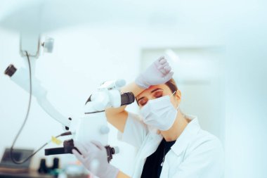 Yorgun Bilimadamı Mikroskop 'a bakarken endişeli hissediyor