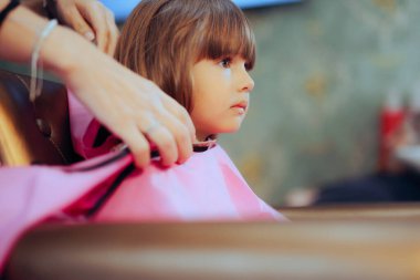 Kuaförde oturmuş, saçını kestirmesini bekleyen küçük kız.