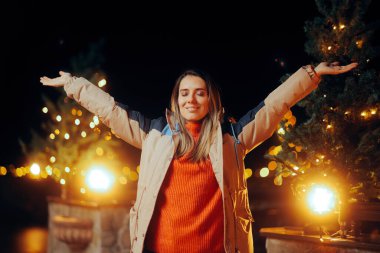 Mutlu kadın kollarını kaldırıyor Noel ışıklarının tadını çıkarıyor