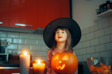Cadı şapkası takan kız gülüyor Cadılar Bayramı süslemelerinin tadını çıkarıyor