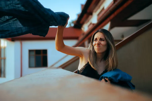 バルコニーの上にボーイフレンドの服を投げる熱心なガールフレンド — ストック写真