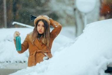 Mutsuz Kadın Deicing spreyi ve bir buz kazıyıcı tutuyor. 