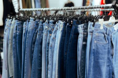 Moda mağazasında bir rafta duran mavi kot pantolonlar.