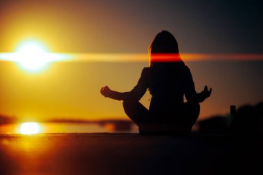 Lotus Pozu 'nda oturan Bir Kadının Silueti Gün Batımına Bakıyor