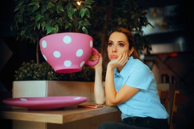 Restoranda kocaman bir fincan kahve içen yorgun bir kadın.