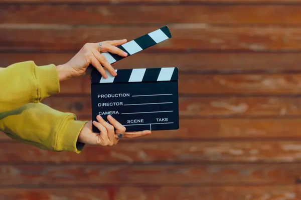 Hand Holding a Film Slate on a Wooden Background