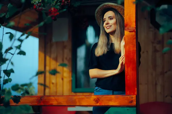 一个头戴草帽的女人站在一个木屋的门廊上 — 图库照片