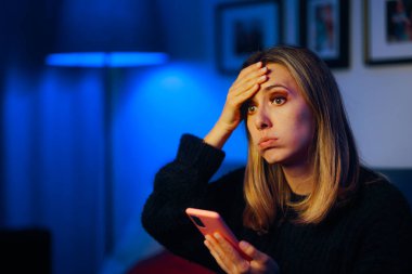 Telefonunu kontrol eden kadın umutsuz ve mutsuz.