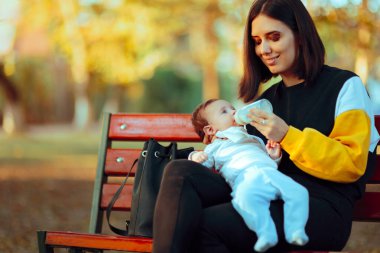 Anne, bebeğini Formula ile parkta besliyor.