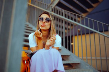 Komik bayan dudak parlatıcısı sürüyor Merdivenlerde oturuyor 