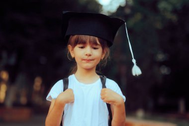 Mezuniyet Mortarboard 'u ve sırt çantası takan mutlu kız. 