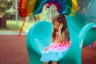 Unhappy Little Girl Holding a Helium Balloon Sitting Alone  clipart