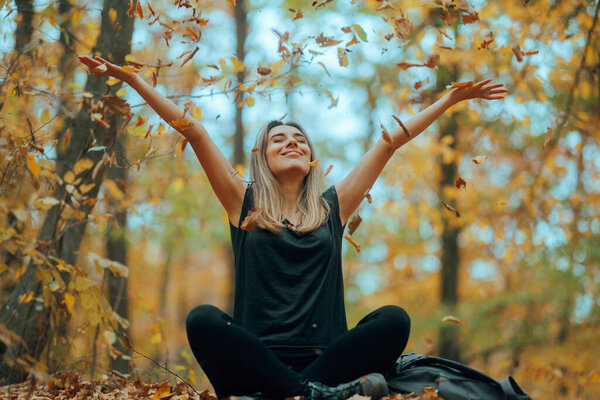 Счастливая женщина бросает сухие листья в воздух