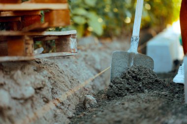 İnşaat işçisi hendek kazmak için kürek kullanıyor