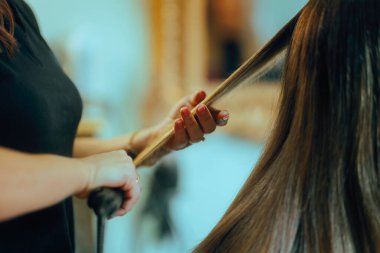 Kuaför, bir kuaförde saç düzleştirici kullanıyor.