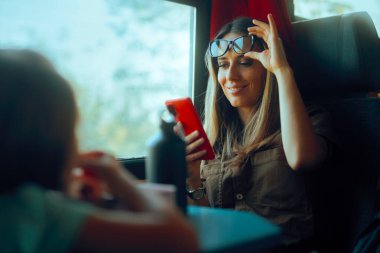 Cep telefonunu yakından okumak için gözlüğünü çıkaran kadın.