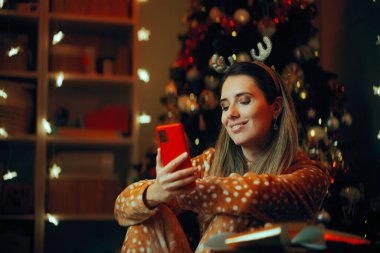Ren Geyiği pijamalı Mutlu Kadın Telefonu kontrol ediyor 