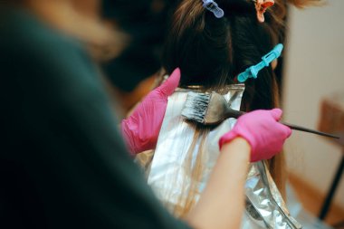 Hairstylist with Hair Dye using Tinfoil to Make Blonde Highlights clipart