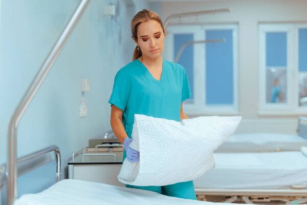 Medical Nurse Preparing Hospital Bed to Receive New Patients