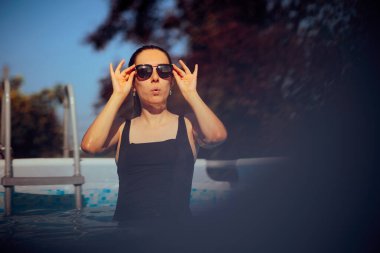 Havuzda güneş gözlüğü takan neşeli yaz kadını.